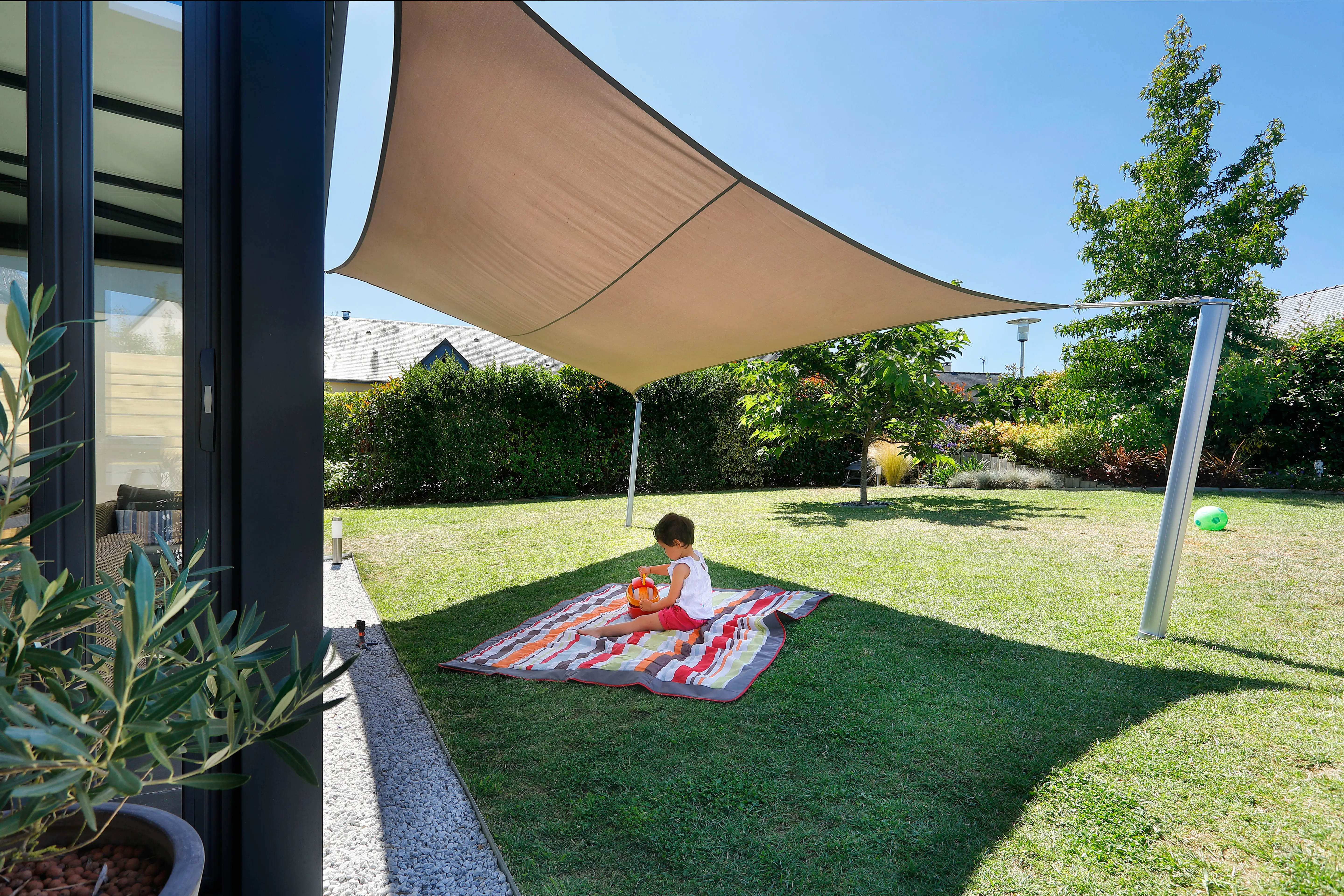 Rectangular shade sail creating shade between a veranda and telescopic shade sail poles